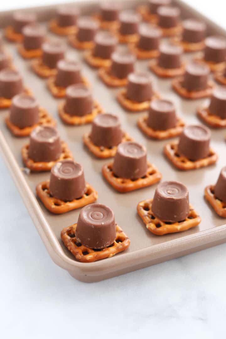 pretzels with Rolos on top of them on baking sheet.