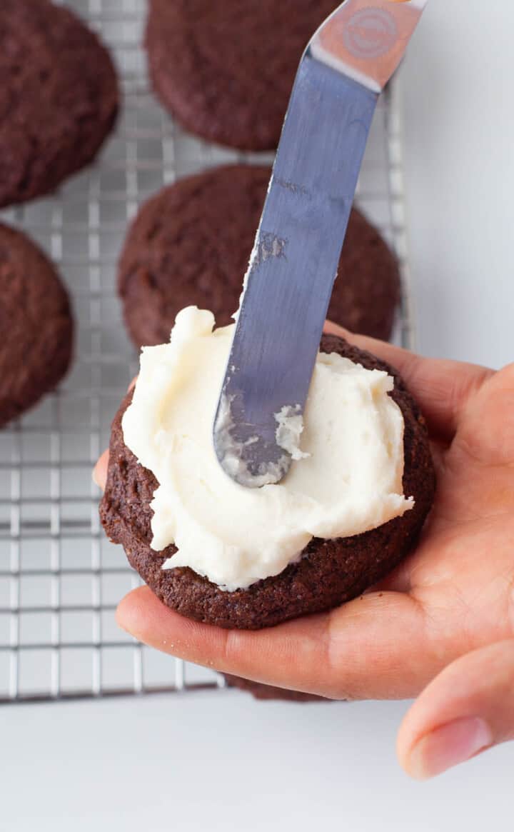 spreading the frosting on the cookie.