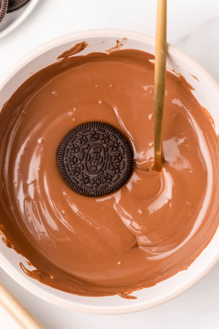 dipping an Oreo in the melted chocolate.