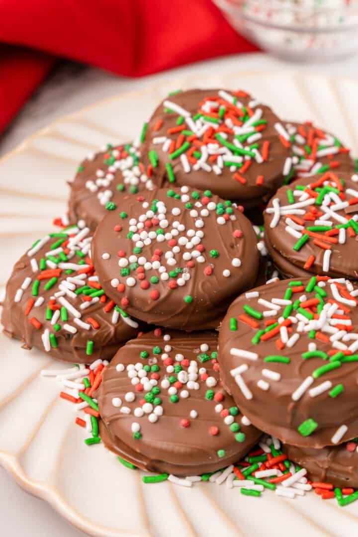 closeup of chocolate covered Oreos stacked on white plate.