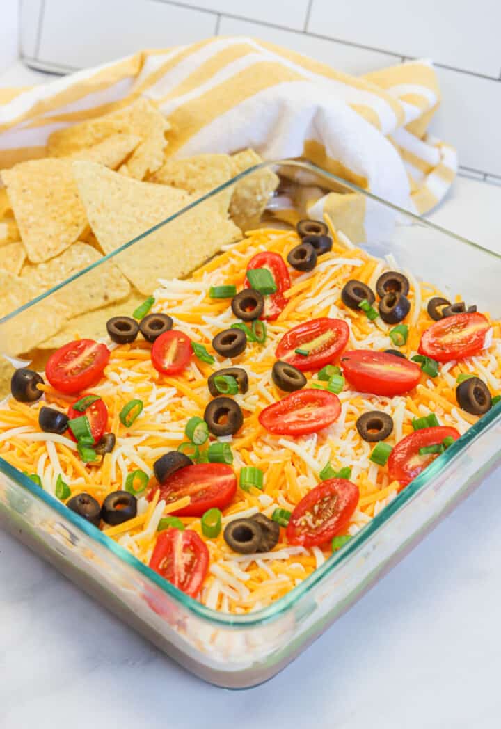 5 layer dip in glass dish with tortilla chips.