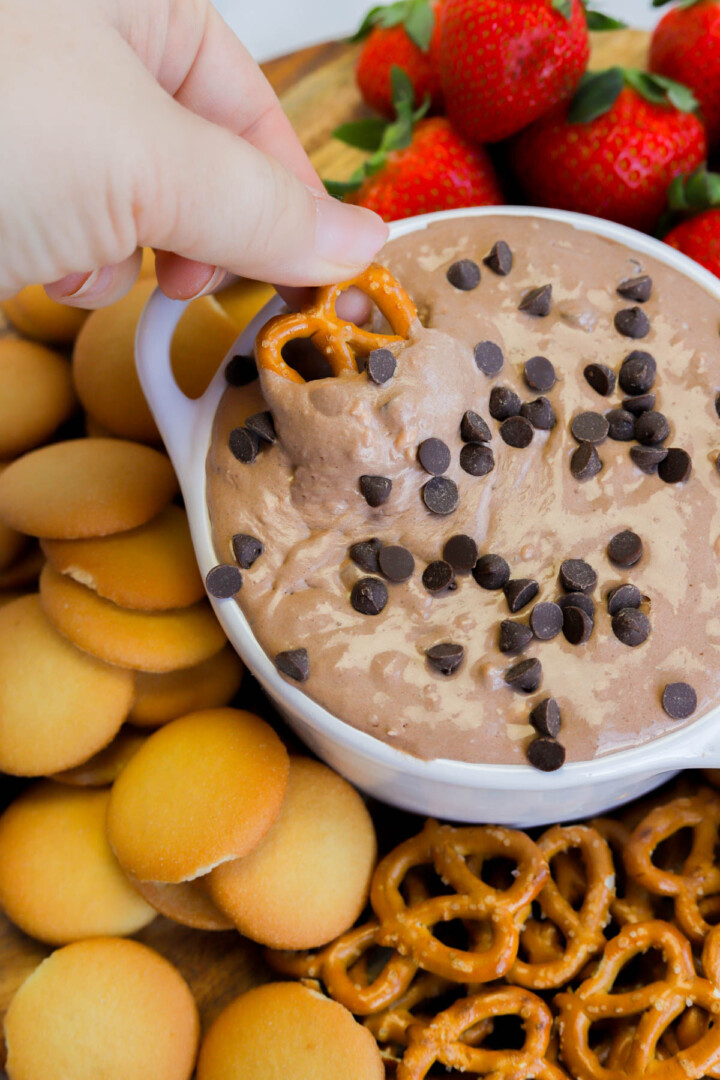 serving the brownie batter dip on wooden board with vanilla wafers, strawberries, and pretzels.