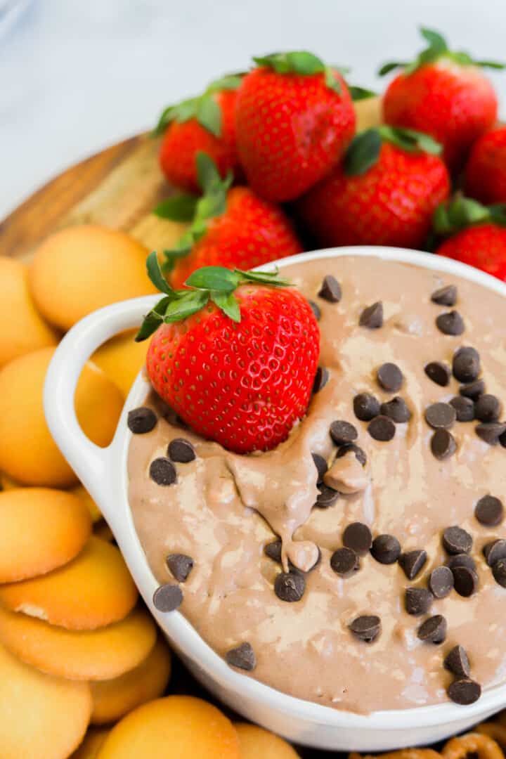 dipping strawberry into the brownie batter dip.