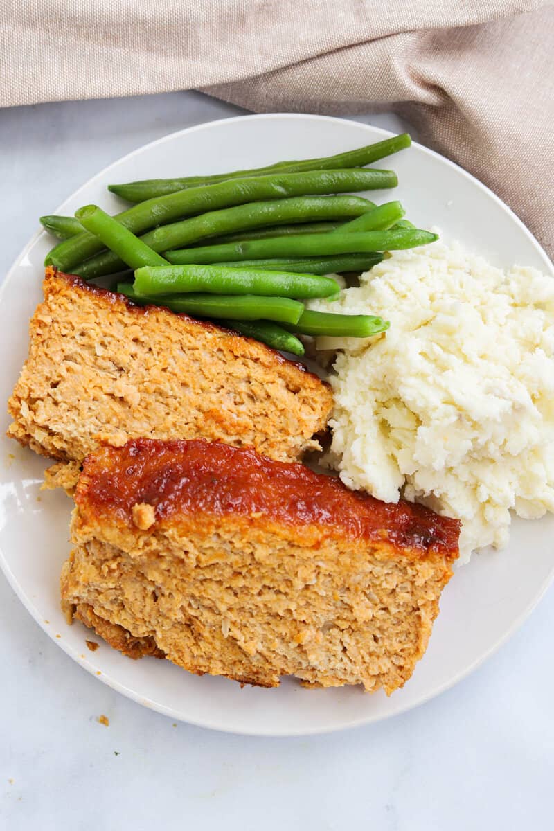 top view of meatloaf on plate with green beans and mashed potatoes.