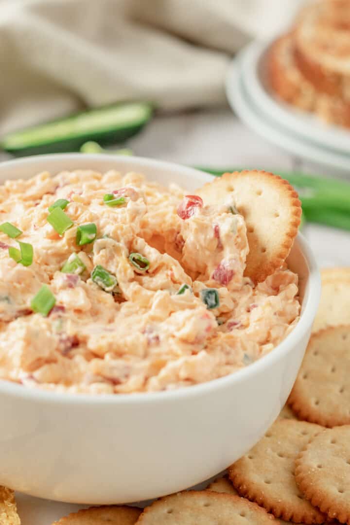 dipping a cracker into the pimento cheese dip.