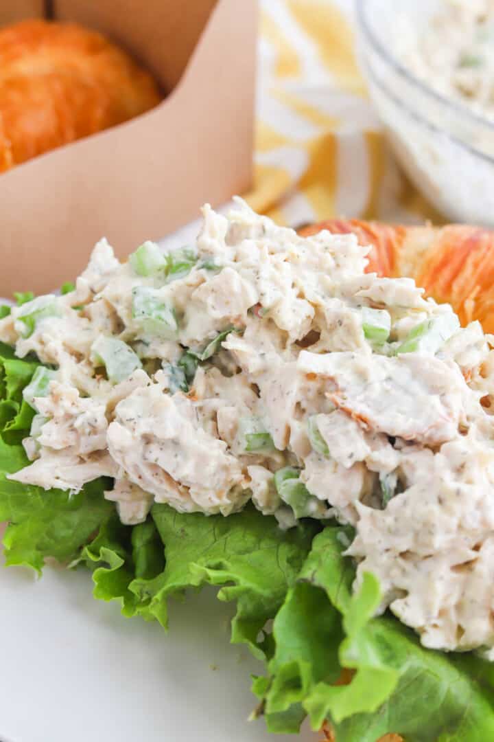 closed up chicken salad on a croissant with lettuce.