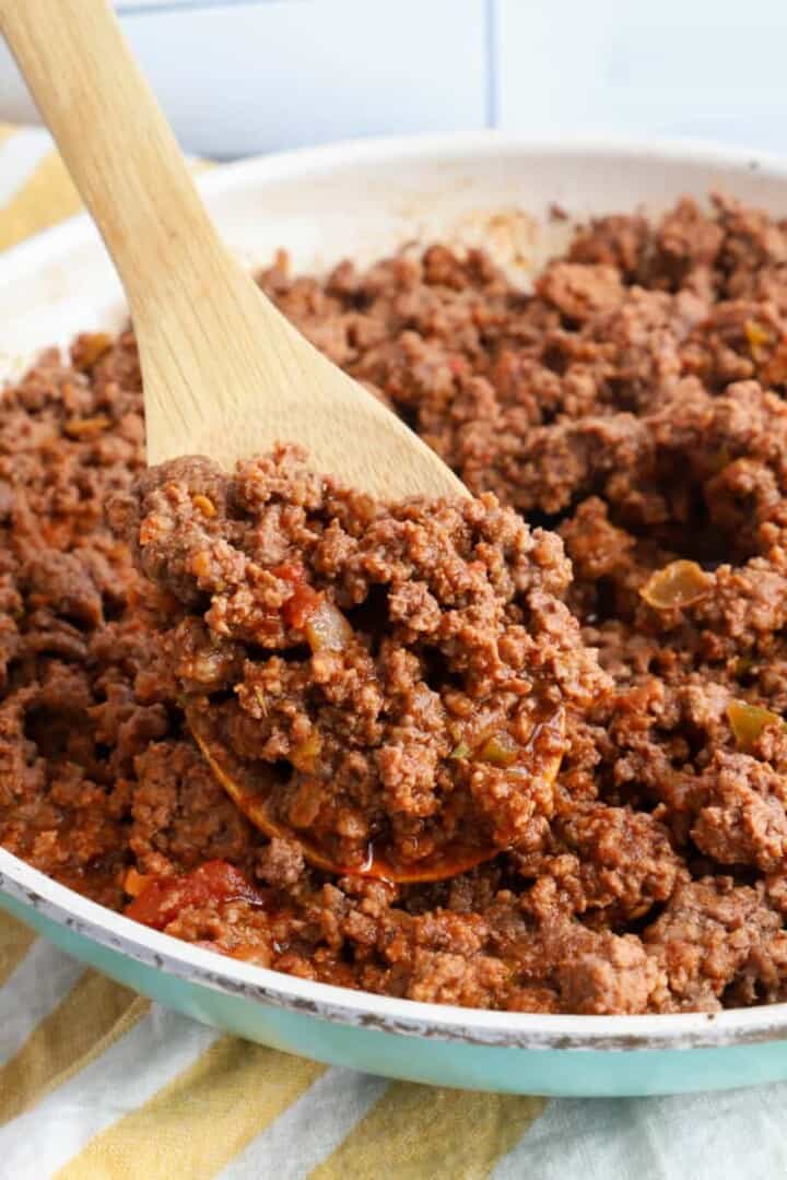 scooping the taco meat out of the skillet with wooden spoon.