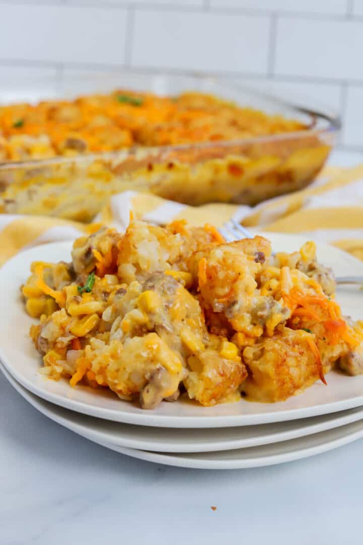 closeup of tater tot casserole on stacked white plates.