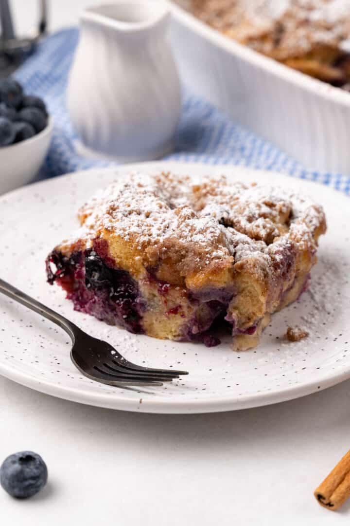 Blueberry French Toast Casserole on white plate with powdered sugar.