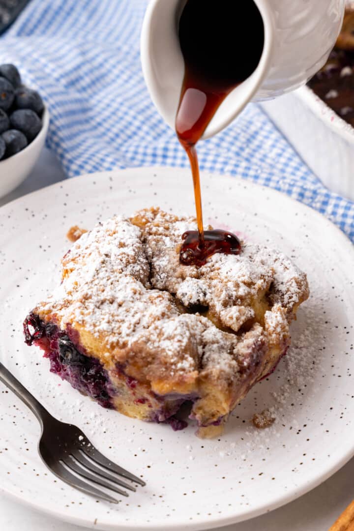 pouring syrup on top of a slice of the casserole.