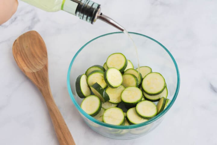 pouring the oil on the zucchini.