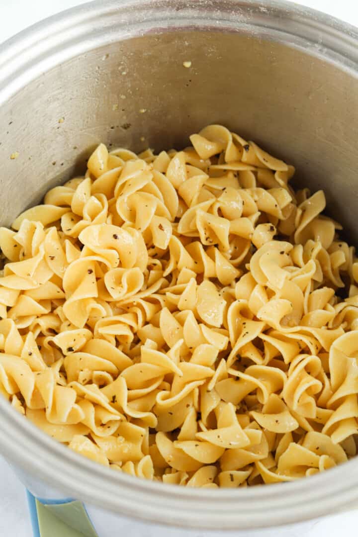 closeup of buttered noodles in large pot.