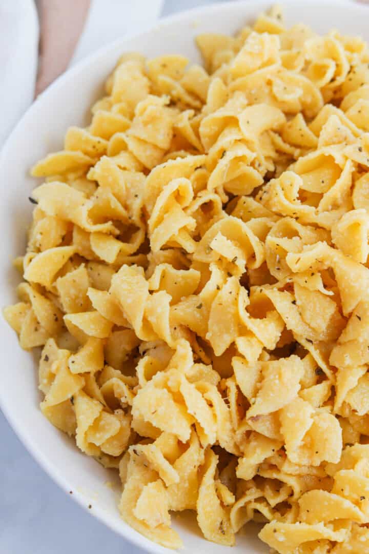 closeup of buttered noodles in white bowl.