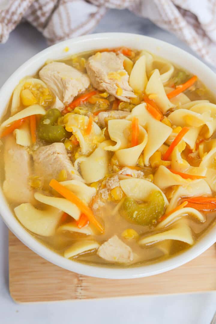 closeup of chicken corn soup in white bowl.