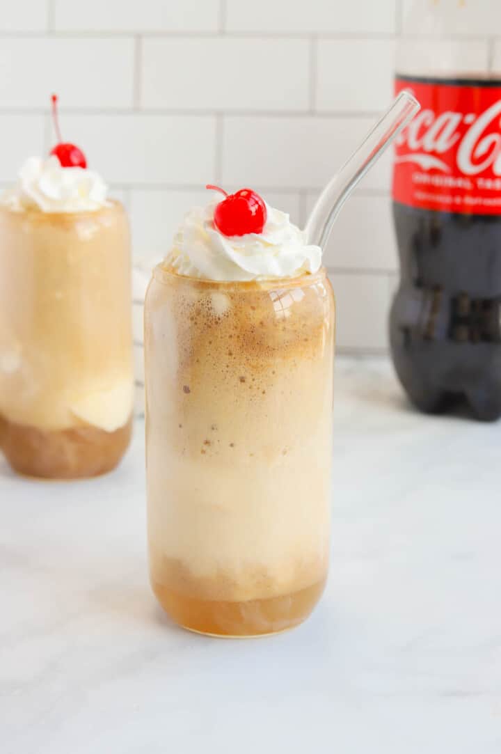 Coke Float in glass topped with whipped cream and a cherry.