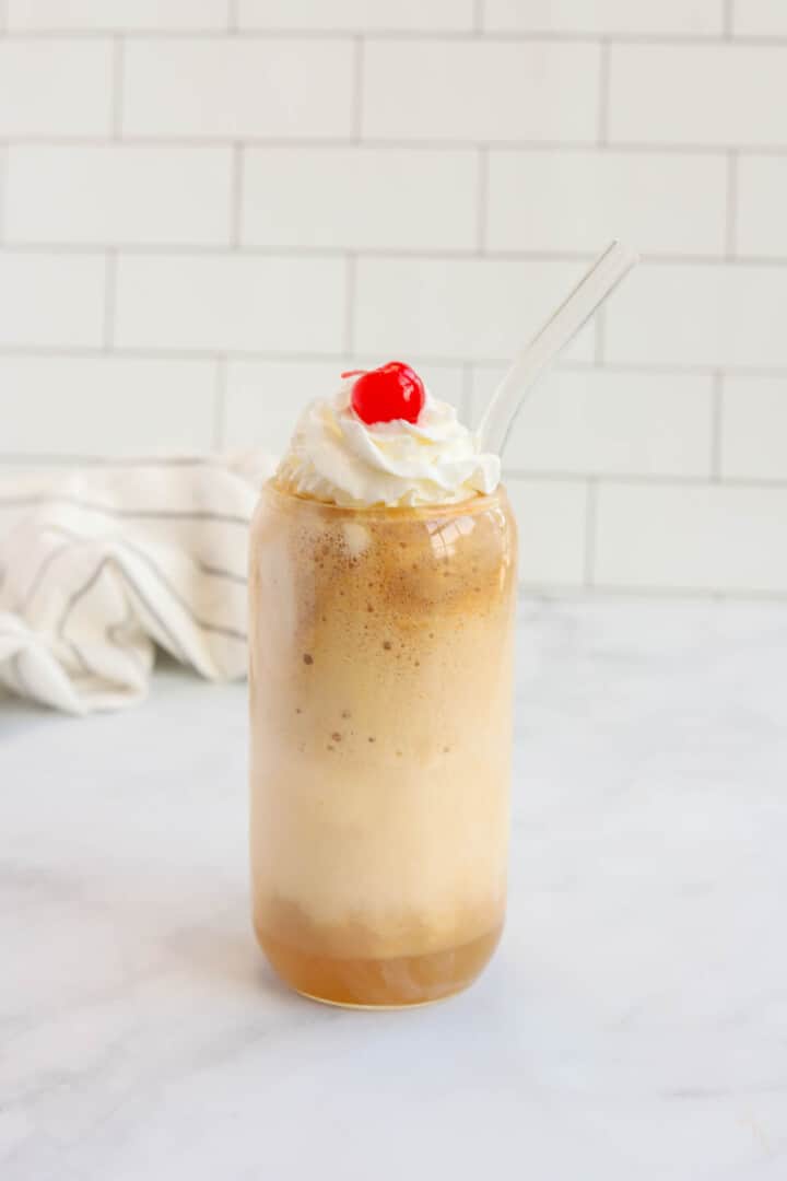 Finished Coke Float in glass topped with whipped cream and cherry.