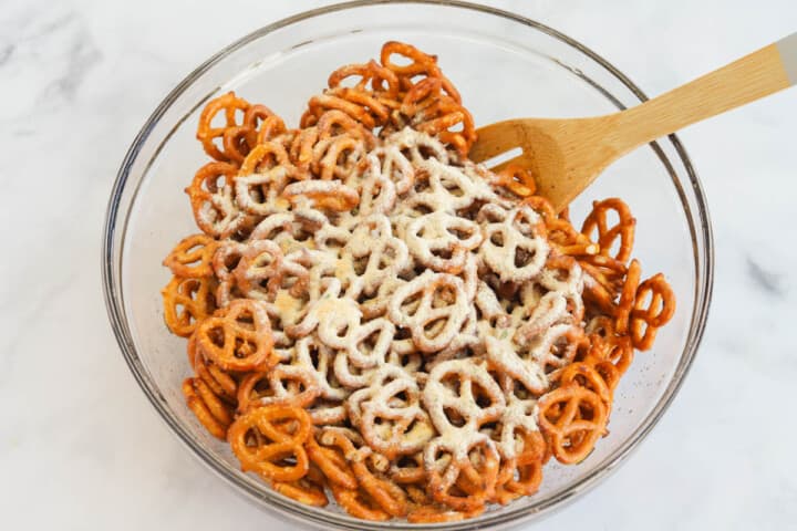 adding the seasoning to the pretzels and mixing.