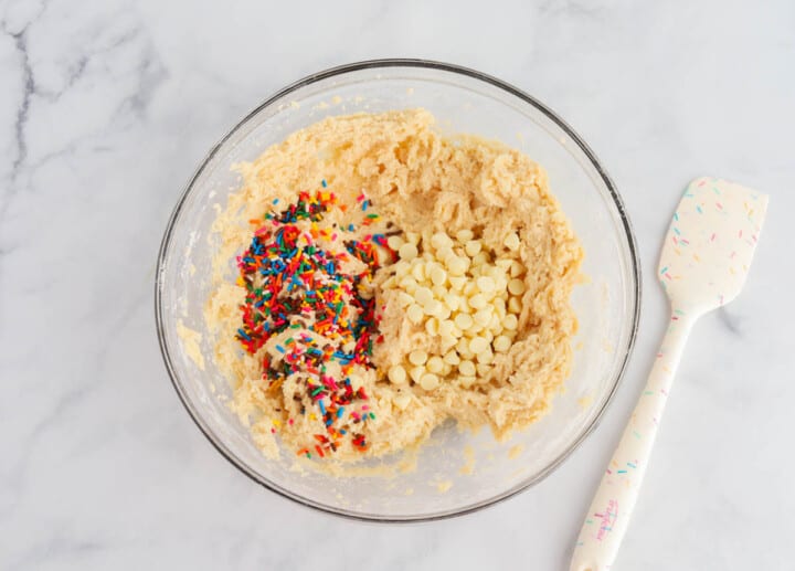 adding the sprinkles and white chocolate chips to the cake batter.