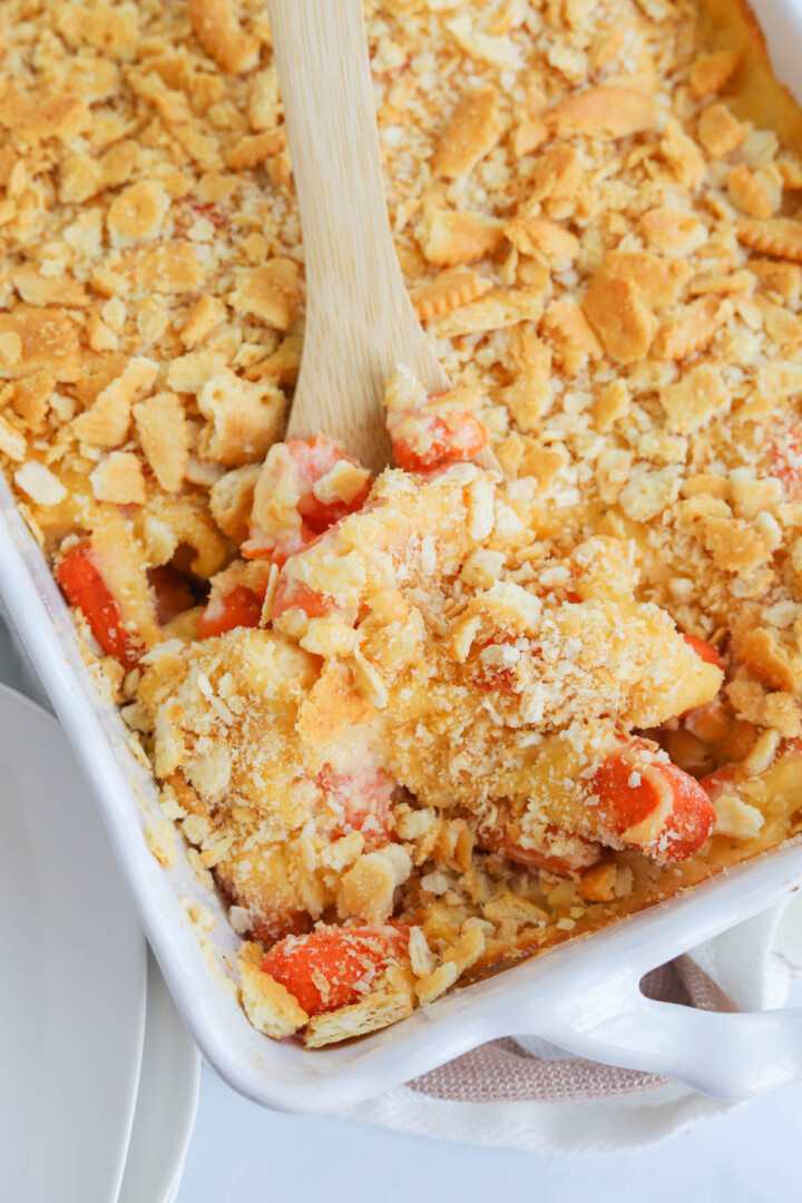 baked carrot casserole being served with wooden spoon.