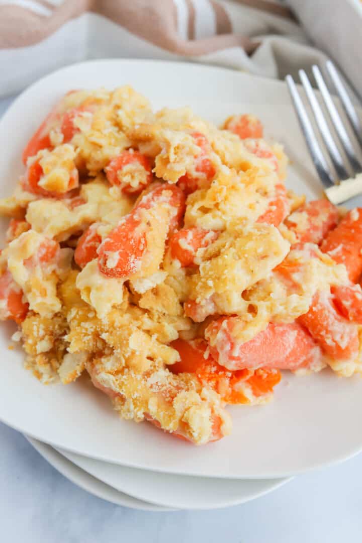 closeup of baked carrot casserole on stacked white plates.