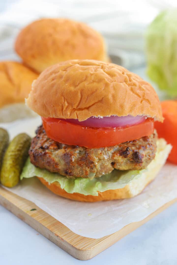 closeup of a turkey burger built on wooden serving board.