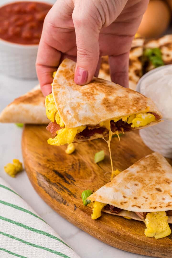 breakfast quesadilla slice in hand.