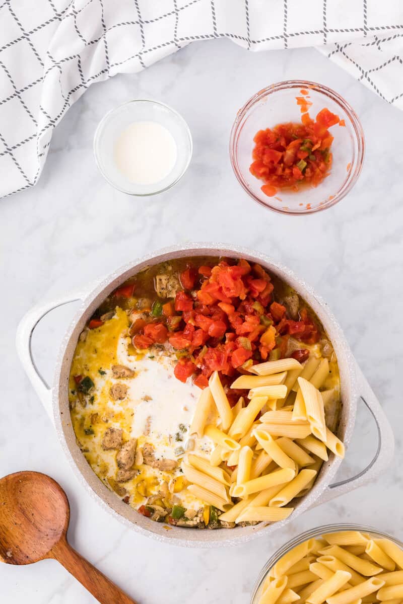 adding cream, tomatoes and noodles to the large pot.