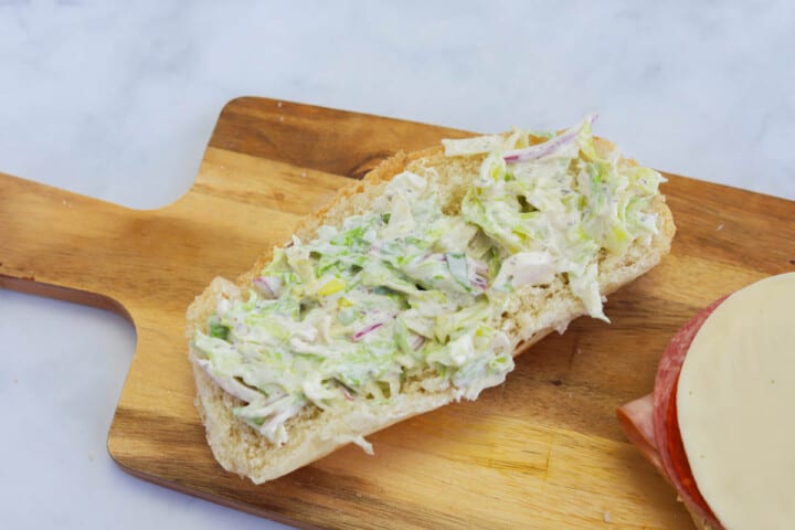 adding the lettuce salad to the top of the grinder.