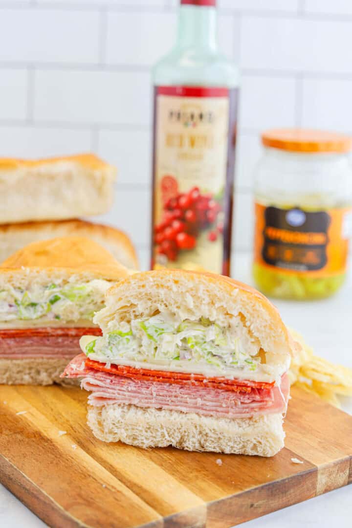 grinder sandwich on wooden board with ingredients in the background.