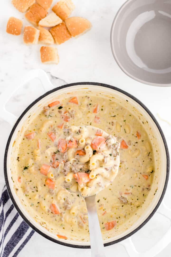 cheeseburger soup in large pot being served with ladle.