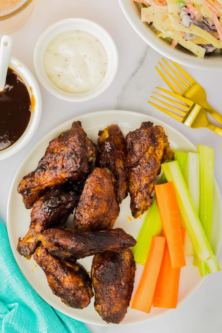 BBQ Chicken Wings on white plate with carrots and celery.
