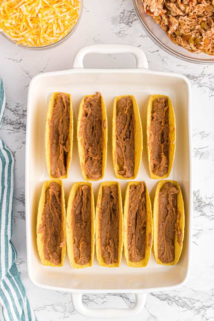 adding refried beans to the taco shells.