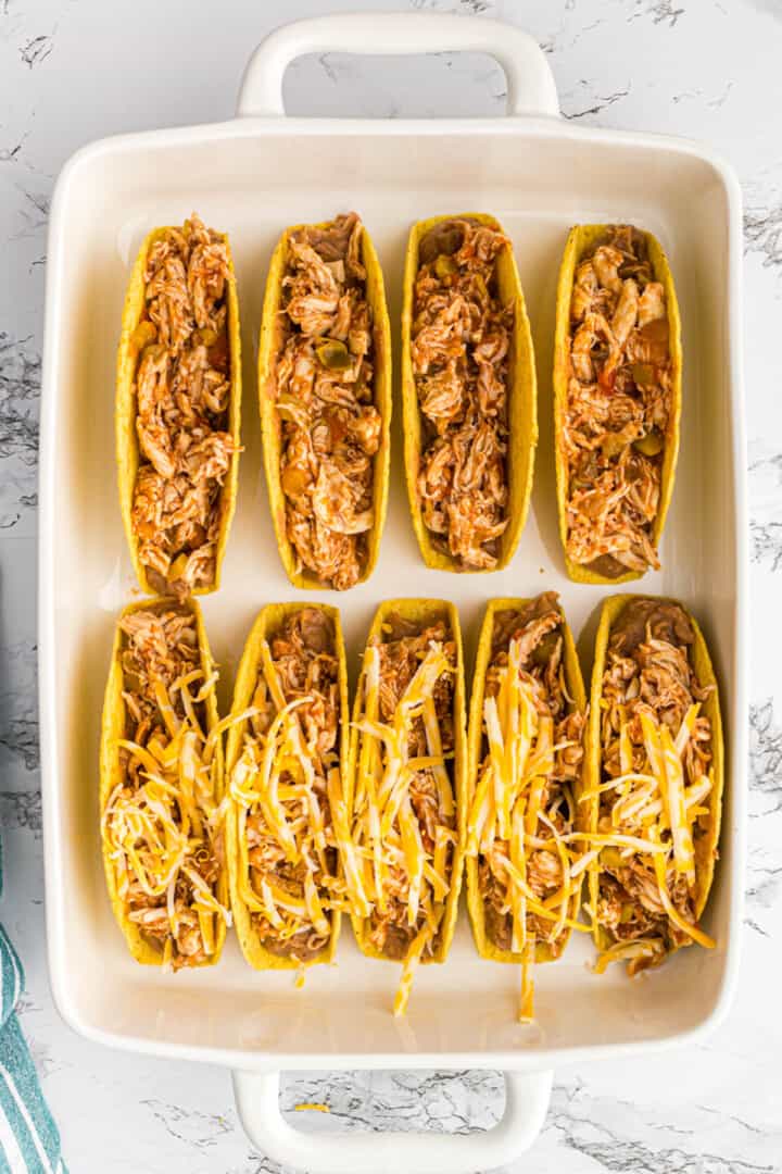 adding the chicken mixture to the tacos with shredded cheese on top.