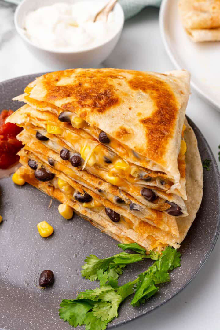 closeup of stacked quesadillas on a black plate.