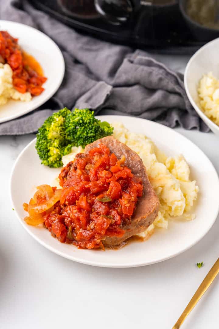 Swiss Steak on white plate with mashed potatoes.