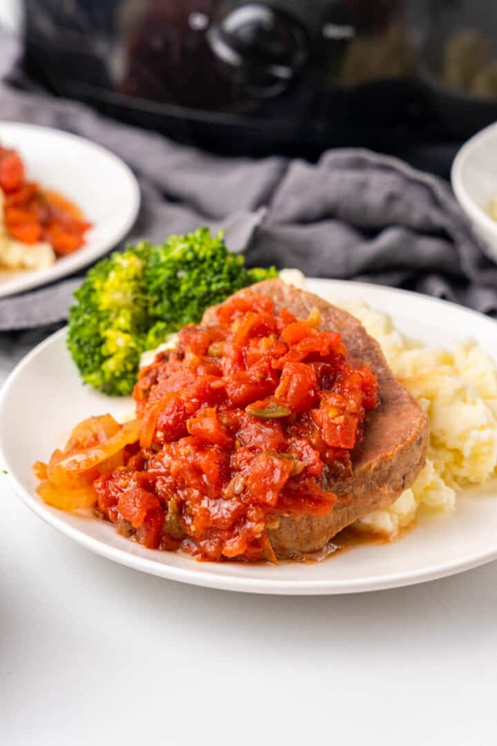 Slow Cooker Swiss Steak on white plate with mashed potatoes.