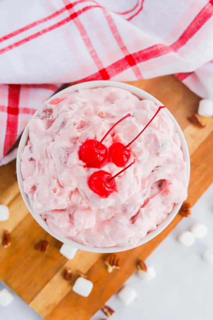 Cherry Fluff in white bowl topped with maraschino cherries.