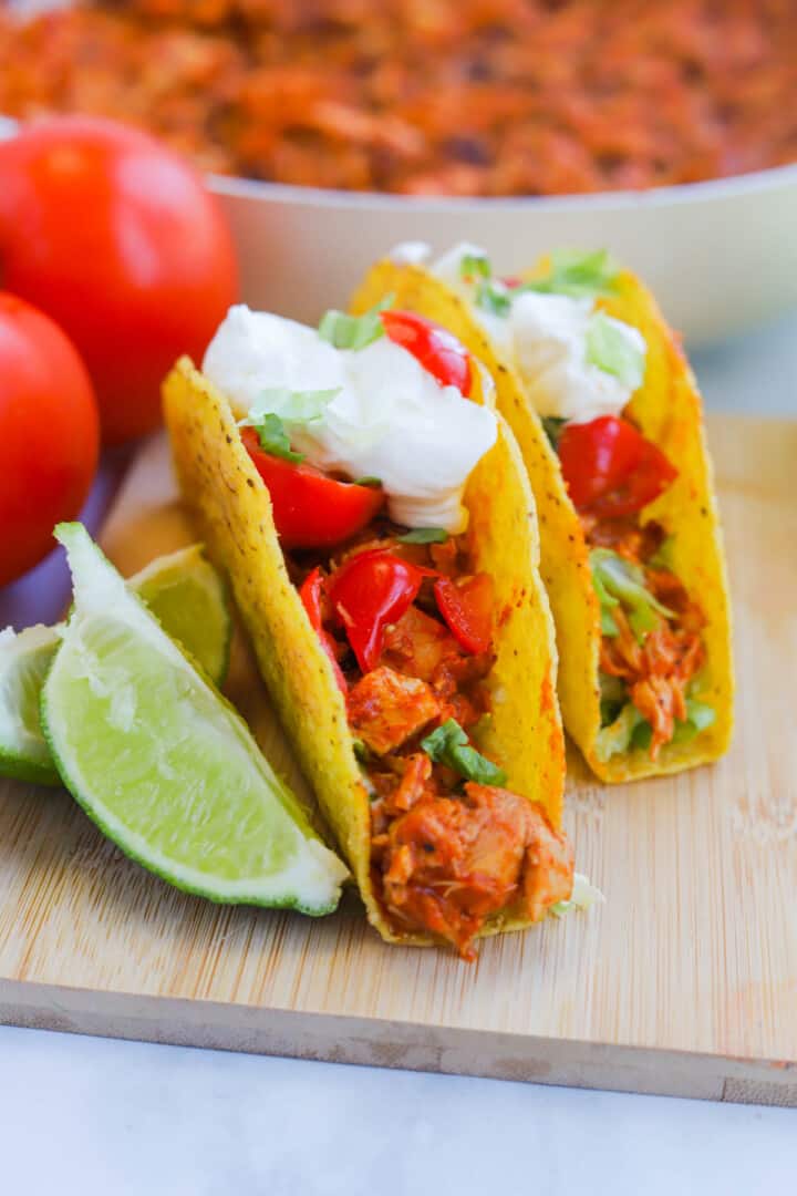 Rotisserie Chicken Tacos on wooden serving board with limes.