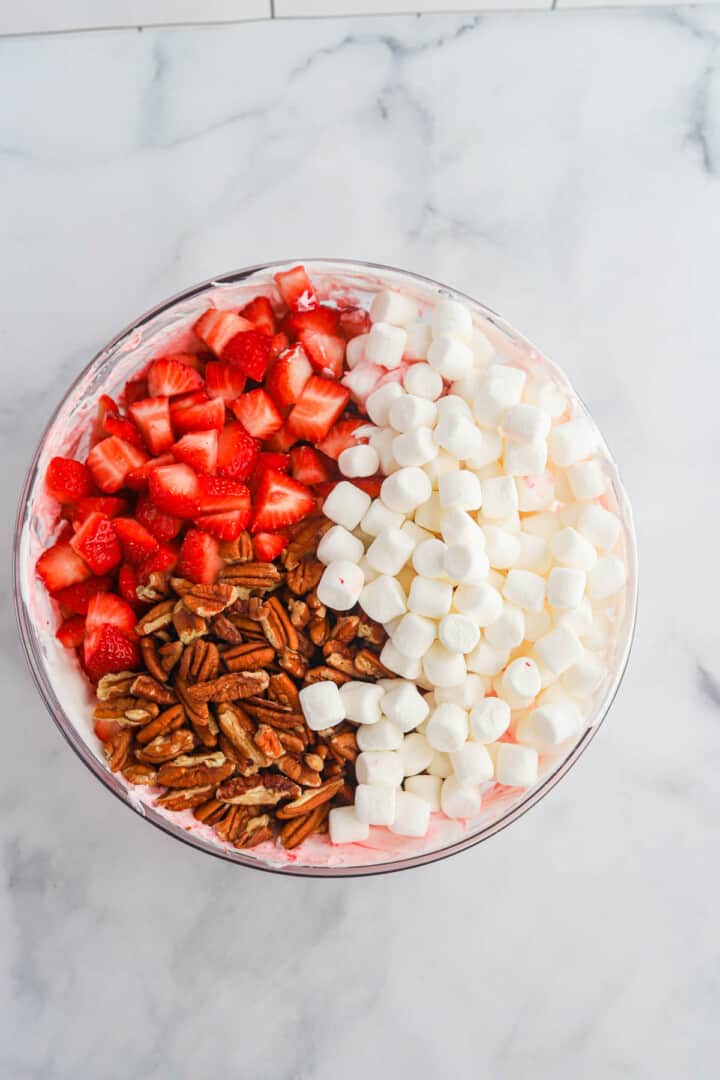 adding the strawberries, marshmallows and pecans to the Jell-O mix.