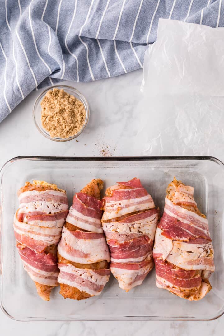 chicken breasts wrapped in bacon in baking dish.