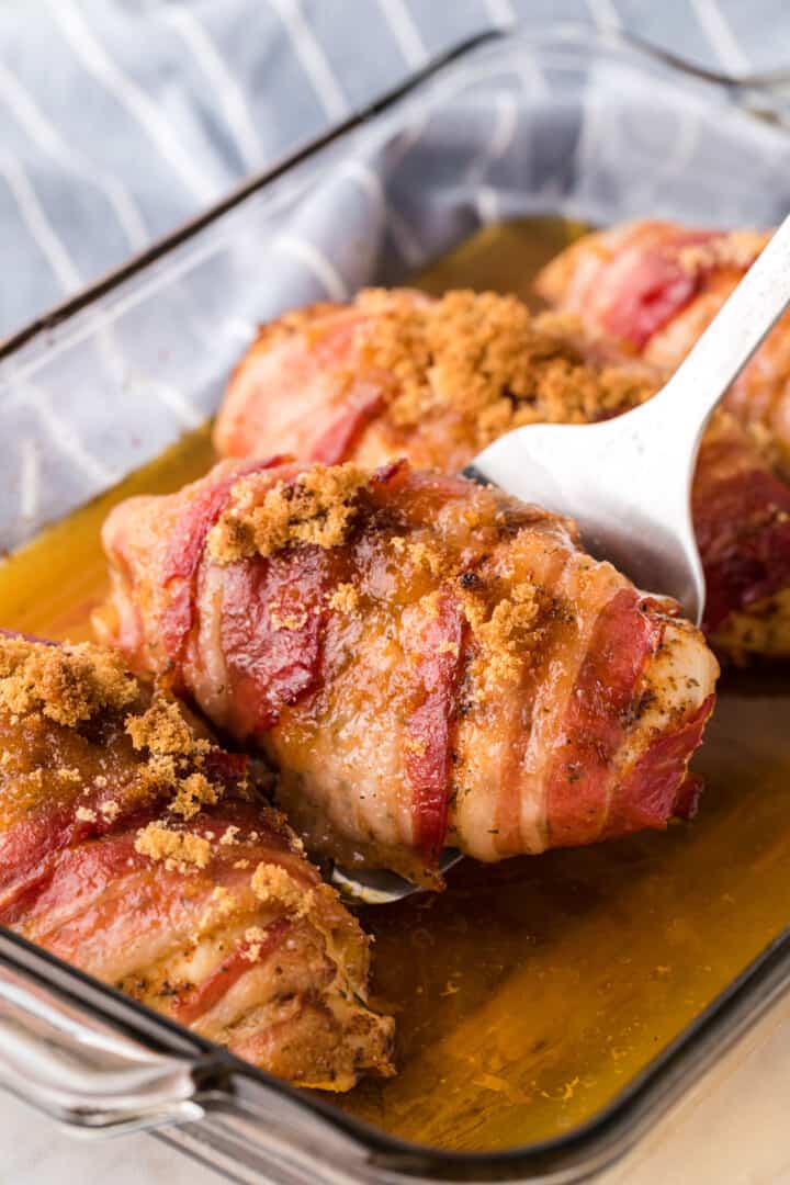 closeup of bacon wrapped chicken breast in baking dish.