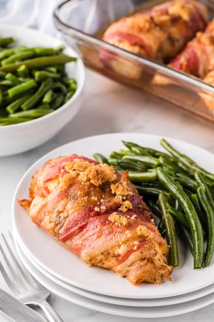 Baked Bacon Wrapped Chicken on plate with green beans.