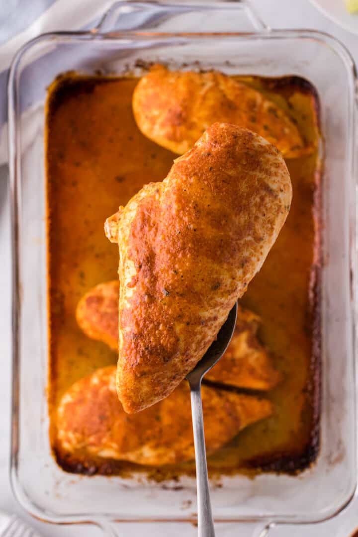 chicken lifted out of the baking dish with fork.