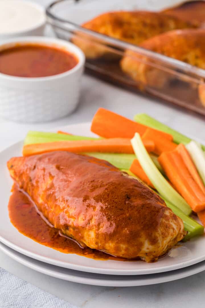 Buffalo Chicken breast on plate with sliced celery and carrots.