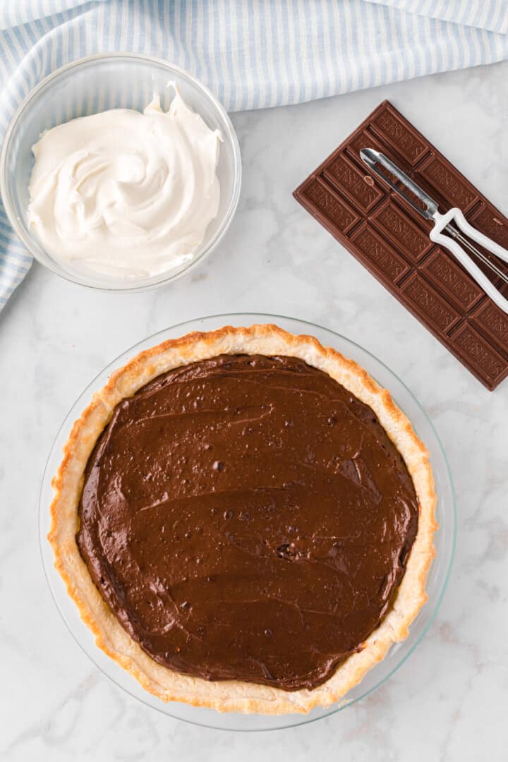 chocolate pudding pie in pie crust with whipped cream in a bowl.