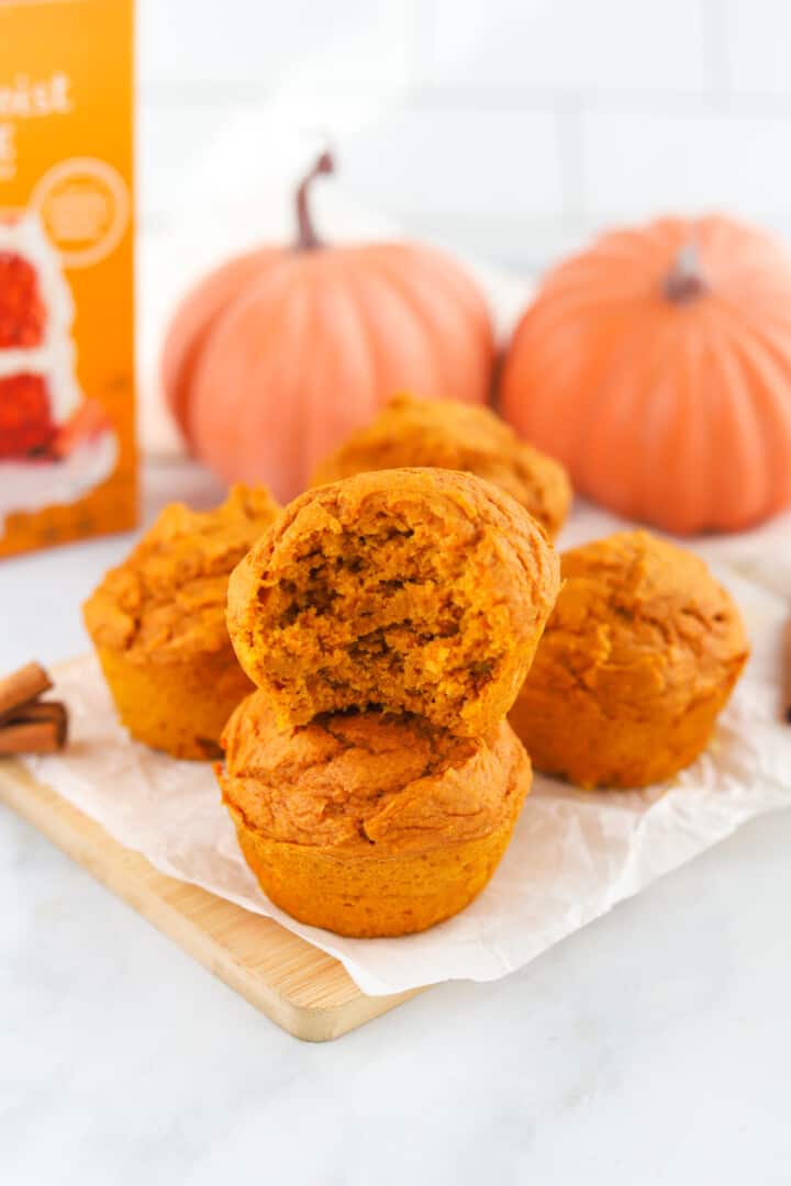 pumpkin muffins stacked on wooden serving board.