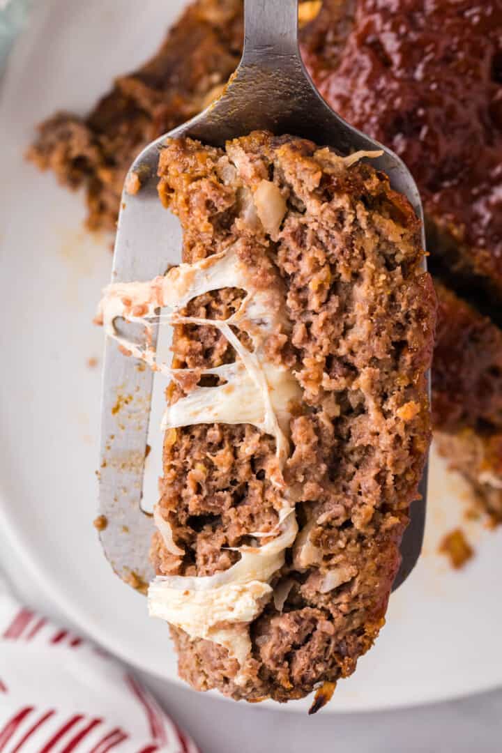 serving a sliced of the stuffed meatloaf.
