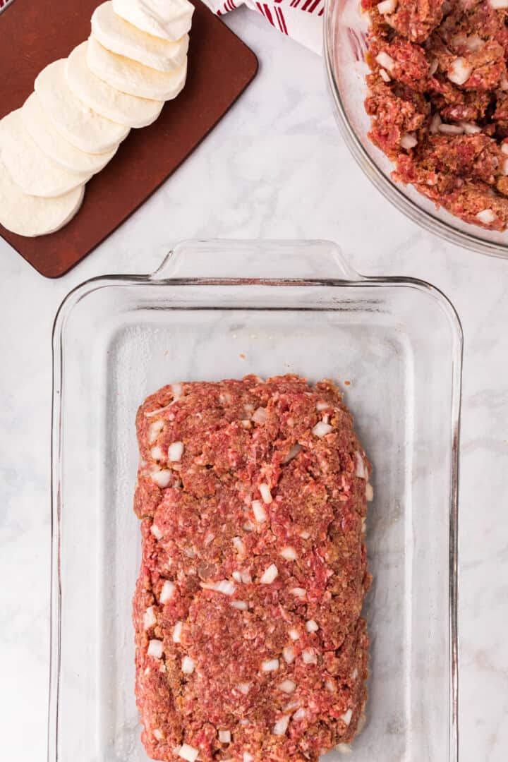 placing half the meatloaf in the bottom of the baking dish.