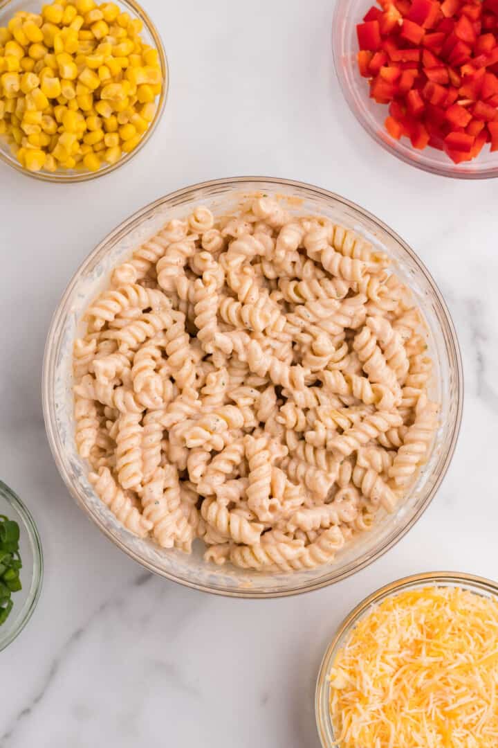 pasta mixed with dressing and other ingredients in bowls.