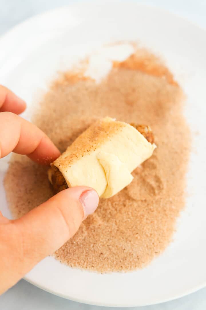 rolling the crescent rolls into the cinnamon sugar mix.